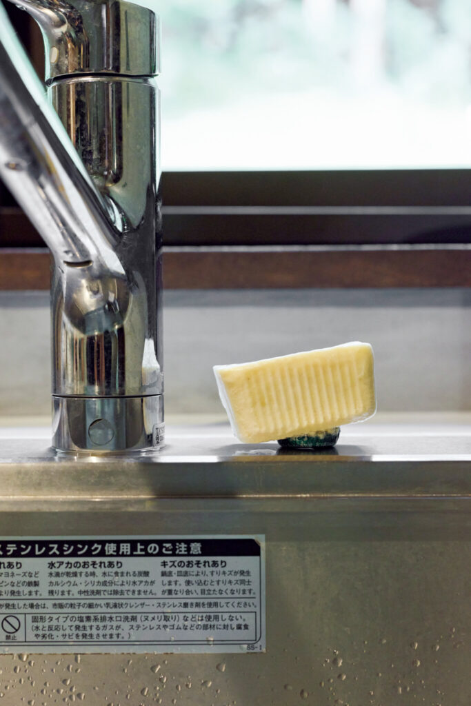 森をのぞむ台所。移ろう景色が家事の支えに。食器洗いはびわこふきんと石鹸を使用。シンクに張り付かないよう石鹸の裏に瓶の蓋を仕込んで浮くように工夫している。 | 食器洗いはびわこふきんと石鹸を使用。シンクに張り付かないよう石鹸の裏に瓶の蓋を仕込んで浮くように工夫している。 森をのぞむ台所。移ろう景色が家事の支えに。食器洗いはびわこふきんと石鹸を使用。シンクに張り付かないよう石鹸の裏に瓶の蓋を仕込んで浮くように工夫している。 | 食器洗いはびわこふきんと石鹸を使用。シンクに張り付かないよう石鹸の裏に瓶の蓋を仕込んで浮くように工夫している。