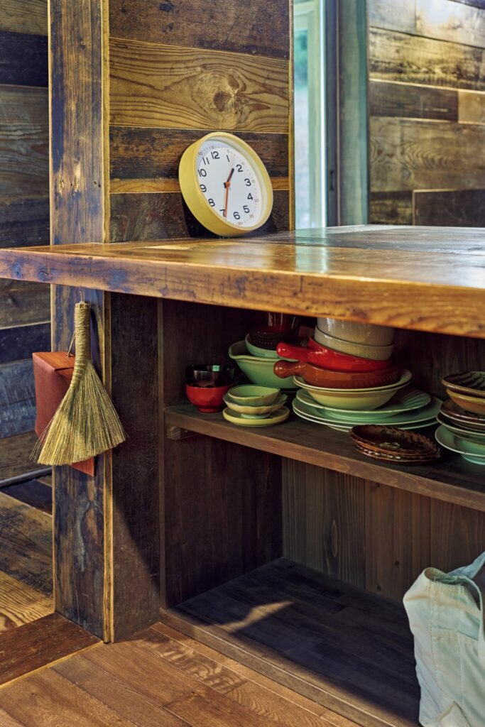 森をのぞむ台所。移ろう景色が家事の支えに。テーブルの下のスペースに棚を付けて器などを収納。オープンラックで取り出しやすい。収納もすべて大工の渡邊覚さんの手によるもの。手ぼうきにはりみ (ちりとり) を愛用。 | テーブルの下のスペースに棚を付けて器などを収納。オープンラックで取り出しやすい。収納もすべて大工の渡邊覚さんの手によるもの。手ぼうきにはりみ(ちりとり)を愛用。 森をのぞむ台所。移ろう景色が家事の支えに。テーブルの下のスペースに棚を付けて器などを収納。オープンラックで取り出しやすい。収納もすべて大工の渡邊覚さんの手によるもの。手ぼうきにはりみ (ちりとり) を愛用。 | テーブルの下のスペースに棚を付けて器などを収納。オープンラックで取り出しやすい。収納もすべて大工の渡邊覚さんの手によるもの。手ぼうきにはりみ(ちりとり)を愛用。