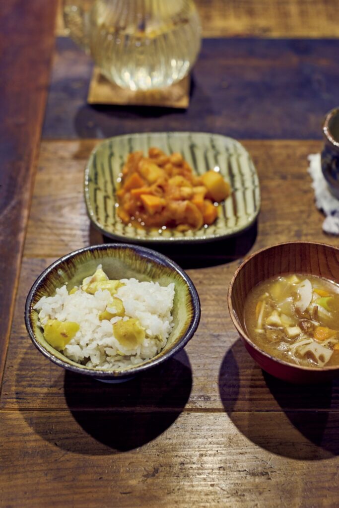 森をのぞむ台所。移ろう景色が家事の支えに。昼食は、栗ご飯に野菜の重ね蒸しの味噌汁。醤油麹で味付けしたひよこ豆とじゃがいものトマト煮。味噌は冬に1年分を仕込むという。 | 昼食は、栗ご飯に野菜の重ね蒸しの味噌汁。醤油麹で味付けしたひよこ豆とじゃがいものトマト煮。味噌は冬に1年分を仕込むという。 森をのぞむ台所。移ろう景色が家事の支えに。昼食は、栗ご飯に野菜の重ね蒸しの味噌汁。醤油麹で味付けしたひよこ豆とじゃがいものトマト煮。味噌は冬に1年分を仕込むという。 | 昼食は、栗ご飯に野菜の重ね蒸しの味噌汁。醤油麹で味付けしたひよこ豆とじゃがいものトマト煮。味噌は冬に1年分を仕込むという。