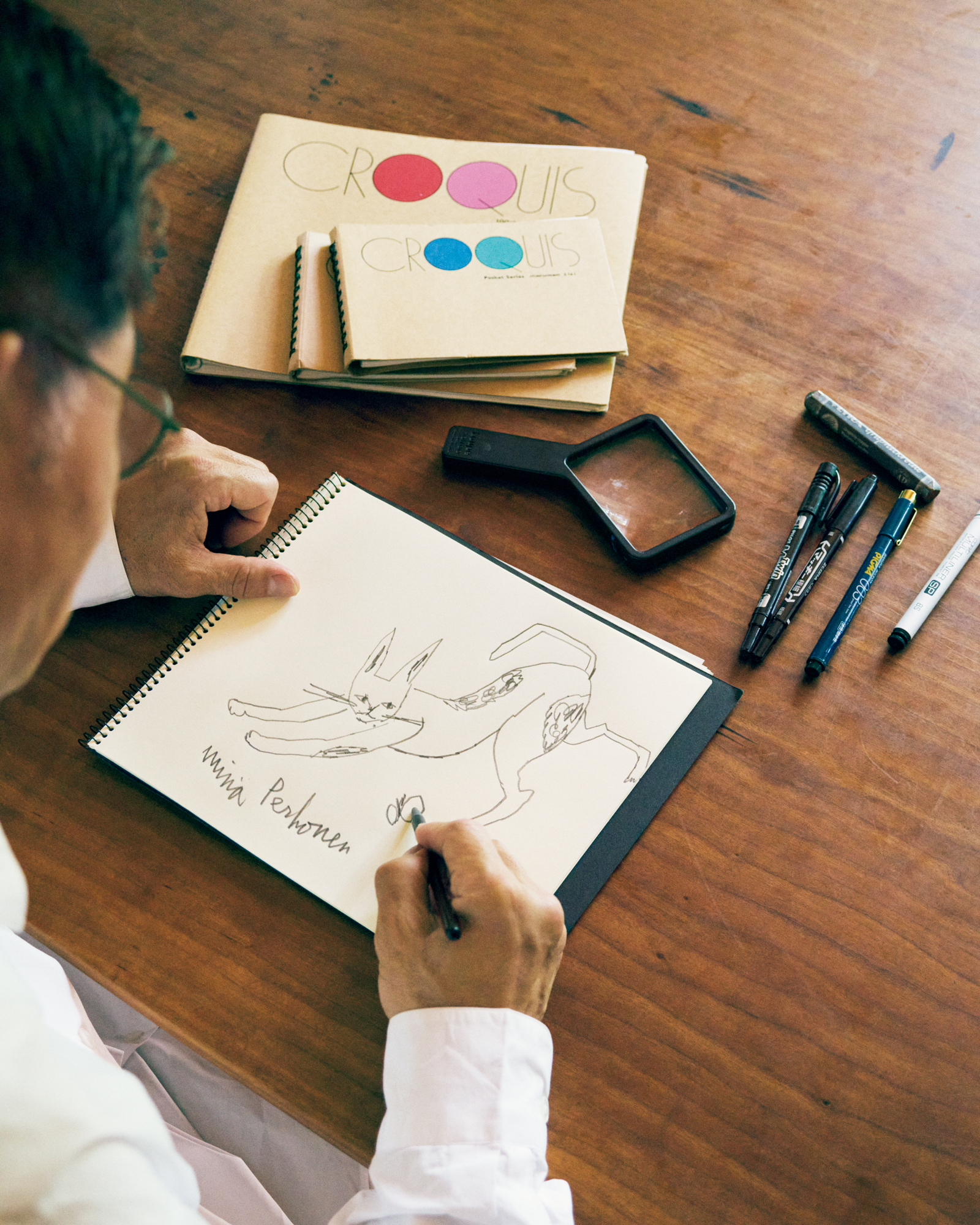 仕事道具の文具から日用品まで。〈ミナ ペルホネン〉デザイナー・皆川 明さんの、日々の暮らしを支えるもの。前編 | スケッチをする皆川さん。よく使う仕事道具は〈マルマン〉のクロッキーブック、〈リラ〉グラファイト鉛筆、〈マッキー〉の油性マーカー、〈デリーター〉ラインドローイングペン、〈モトデザイン〉のルーペなど、比較的手に入りやすいスタンダードな文房具を長年愛用している。