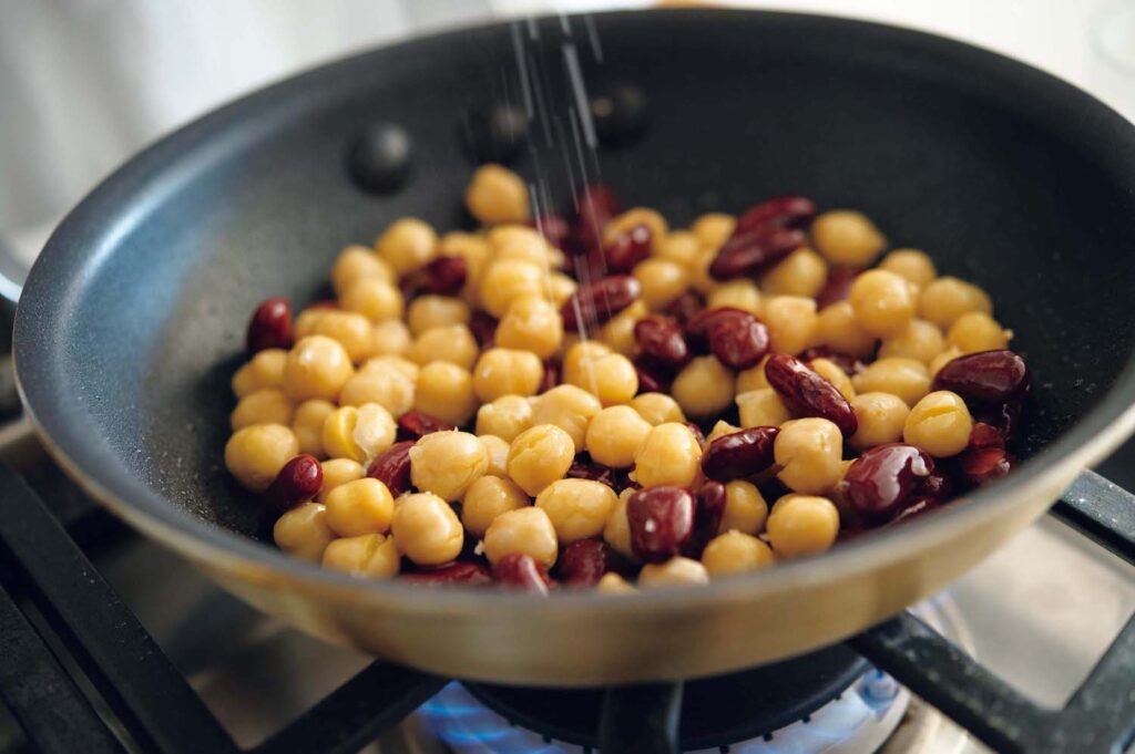 &CookingM_p006-053_献立編_25 | オリーブオイルにチリパウダーを入れ、香りが立ってから2種の豆を炒める。