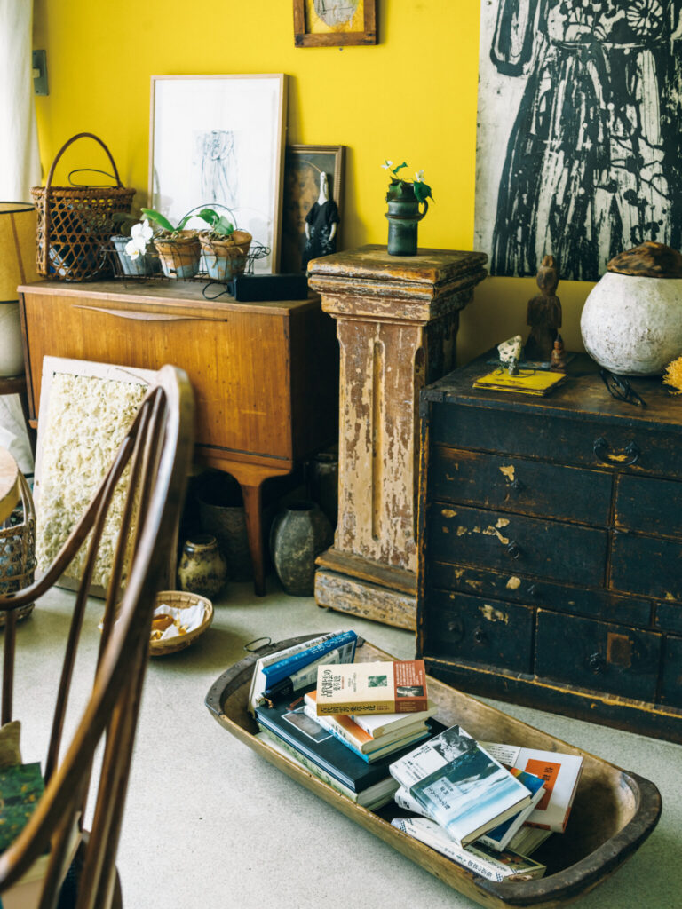 フラワーデザイナー・市村美佳子さんの本のある風景。「住む人を映す、本棚」02。「本を積むのにいいと思って」と友人から最近譲り受けた古い木器に、愛読書を。様々な国や時代のモノが入り交じる自宅兼アトリエにて。