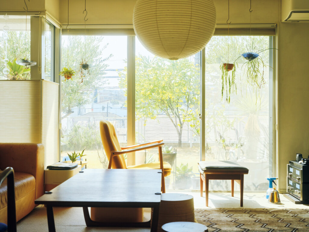 バッグデザイナー・石川敦幹さんが植物と暮らす家。空間に調和する、グリーンの整え方。石川敦幹さんの家のリビングは目の前に庭が広がり、開放的。〈プラセールワークショップ〉の鉢をメインにレールにグリーンをハンギングして、室内外で緑を愛でる。
