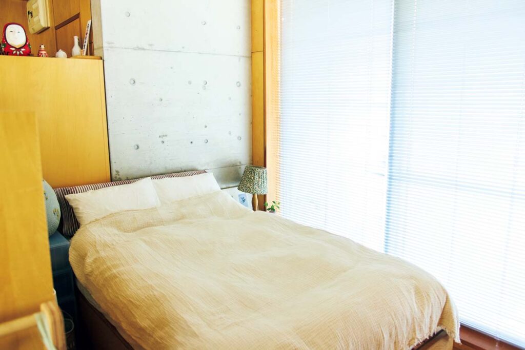 間仕切りを兼ねる収納の裏がベッドスペース。〈ミナ ペルホネン〉のテキスタイルを使ったクッションや照明などが置かれ、余白を残したスペースに。