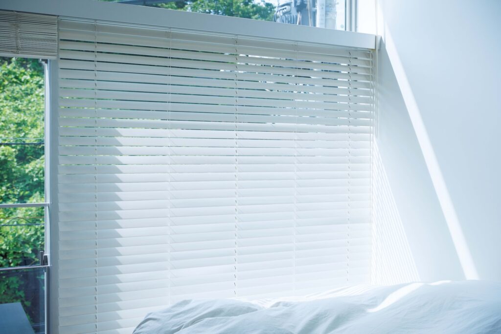 窓は天井まであるが、上下別々にブラインドが付けられているので、遮光の塩梅を操作しやすい。「ベッドにこぼれる光と、一期一会の影がきれいなんです」