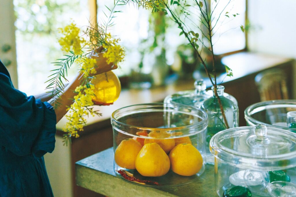 葉の細い品種を探して植えたミモザを挿したのは、横山秀樹の黄色い花器。庭で採れた晩柑との色合わせも美しい。