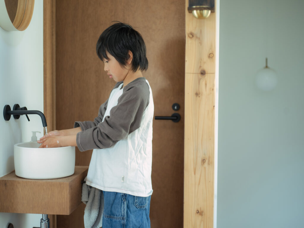 お手洗い近くにあるコンパクトな洗面台で手洗いする、9歳の長男。