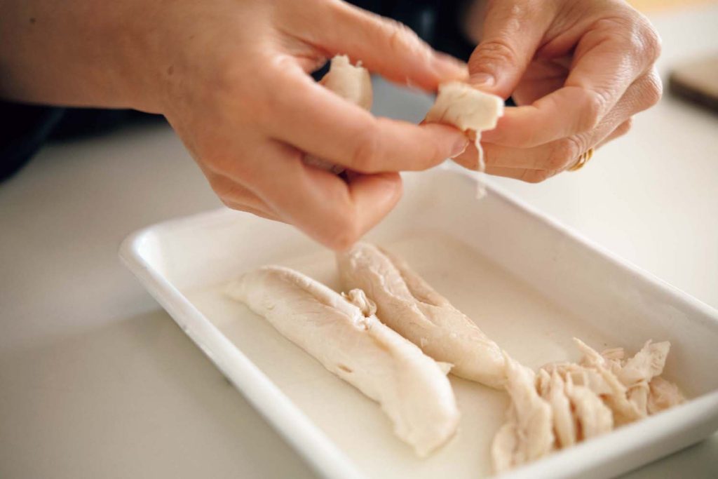 蒸した日に、涼やかな料理とデザート。渡辺有子の料理教室3年目6月 | 筋を取った鶏ササミを沸騰した湯に入れ、火を弱めて茹でる。繊維に沿ってほぐす。