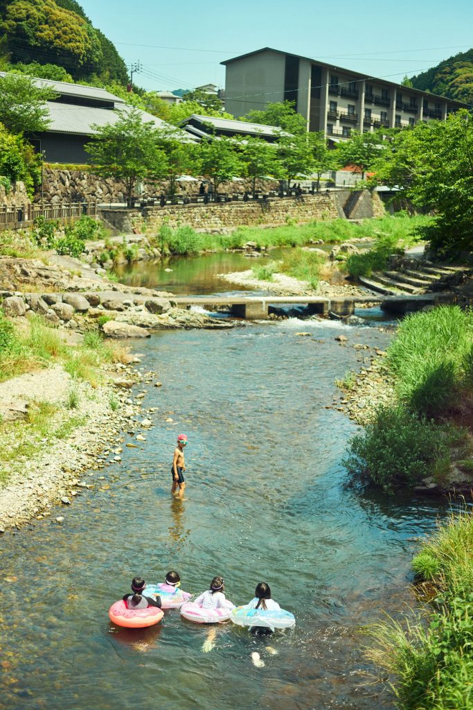 温泉街の真ん中を流れる澄んだ音信川で、水浴びを楽しむ近所の子どもたち。こんなノスタルジーをそそる光景が見られるのも魅力。 | 温泉街の真ん中を流れる澄んだ音信川で、水浴びを楽しむ近所の子どもたち。こんな郷愁を誘う光景が見られるのも魅力。