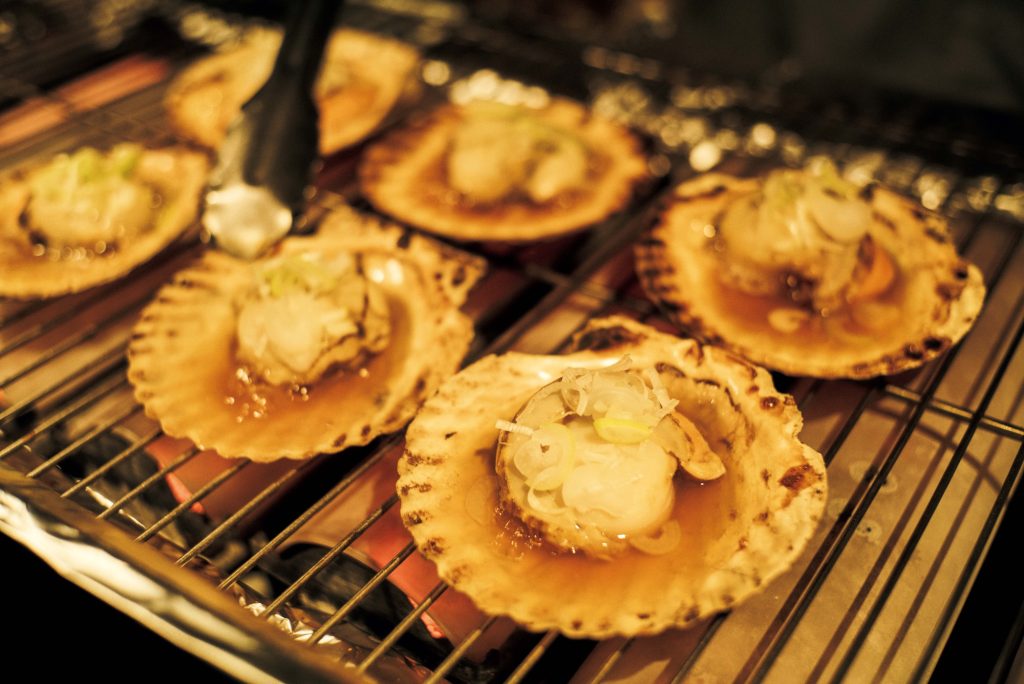 「のれそれ食堂」では、目の前で焼いてくれるホタテやサーモン、サバの炉端焼きを。あたたかな伝統文化ともてなしに触れる。穏やかな時間が流れる『青森屋』へ。坂本美雨さんと巡る、青森への旅。 | 「のれそれ食堂」では、目の前で焼いてくれるホタテやサーモン、サバの炉端焼きを。