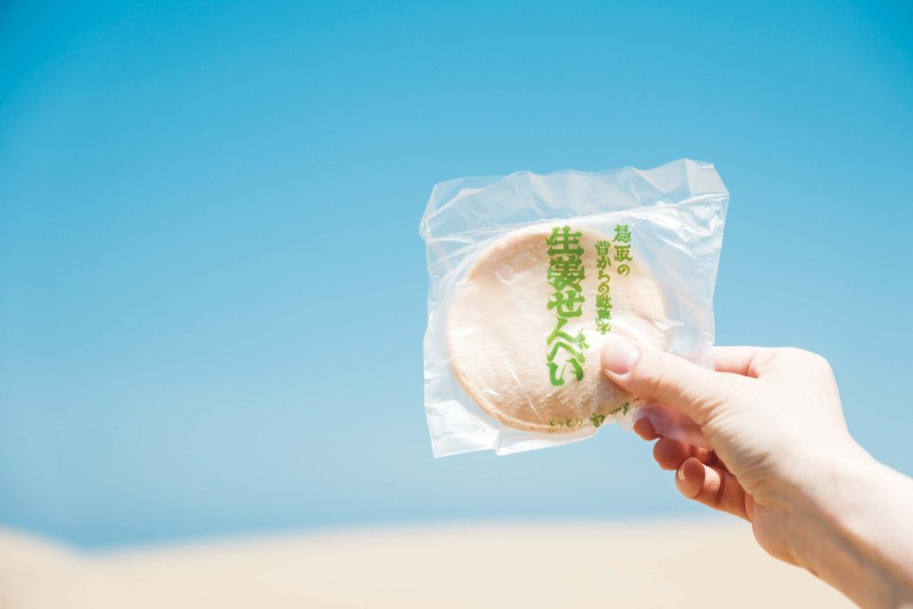 手仕事を辿る旅。鳥取・鳥取〜倉吉で出合った18のスポット。 | 江戸後期から伝わる郷土菓子「生姜せんべい」。白く刷（は）いた蜜を吉田璋也は「鳥取砂丘にうっすら雪が積もったようだ」と表現した。波打つ姿は砂丘を模したもの。明治35年創業の『宝月堂』（鳥取市二階町3‒121）では手仕事で焼き上げている。