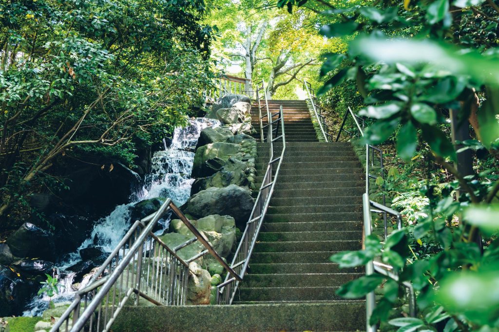 建築やアートを巡る旅。石川・金沢で出合った17のスポット。前編　美術の小径　 『石川県立歴史博物館』から本多の森公園沿いに歩き、隣接する『石川県立美術館』の裏手へ回ると、うっそうとした緑に囲まれた石段『美術の小径』（金沢市本多町3）が見えてくる。辰巳用水の水が滝のように流れ落ち、ちょっとした山登り気分も味わえるリフレッシュエリアだ。「金沢は水と緑が豊かな街でもあります。それを象徴するような気持ちいい散歩道です」。途中で石垣などの遺構がある『歴史の小径』に分岐する。 | 美術の小径
『石川県立歴史博物館』から本多の森公園沿いに歩き、隣接する『石川県立美術館』の裏手へ回ると、うっそうとした緑に囲まれた石段『美術の小径』（金沢市本多町3）が見えてくる。辰巳用水の水が滝のように流れ落ち、ちょっとした山登り気分も味わえるリフレッシュエリアだ。「金沢は水と緑が豊かな街でもあります。それを象徴するような気持ちいい散歩道です」。途中で石垣などの遺構がある『歴史の小径』に分岐する。