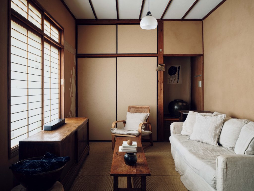 自分たちらしい空間に、家を育てていく。『hitonoto』店主・安田奈央さんとビデオグラファー・ニック・ヴァン・デル・ギーセンさんの築60年のお家。リビングは、夜になると障子の前にスクリーンを下ろしてムービールームに。床はサイザル地に張り替えている。 | リビングは、夜になると障子の前にスクリーンを下ろしてムービールームに。床はサイザル地に張り替えている。