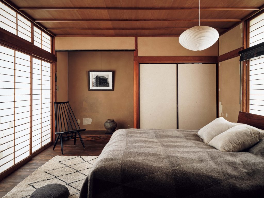 自分たちらしい空間に、家を育てていく。『hitonoto』店主・安田奈央さんとビデオグラファー・ニック・ヴァン・デル・ギーセンさんの築60年のお家。 | 2階の寝室も落ち着いた和空間。床の間にはニックさん自身が能登で撮影したツタに覆われた空き家が印象的な風景。