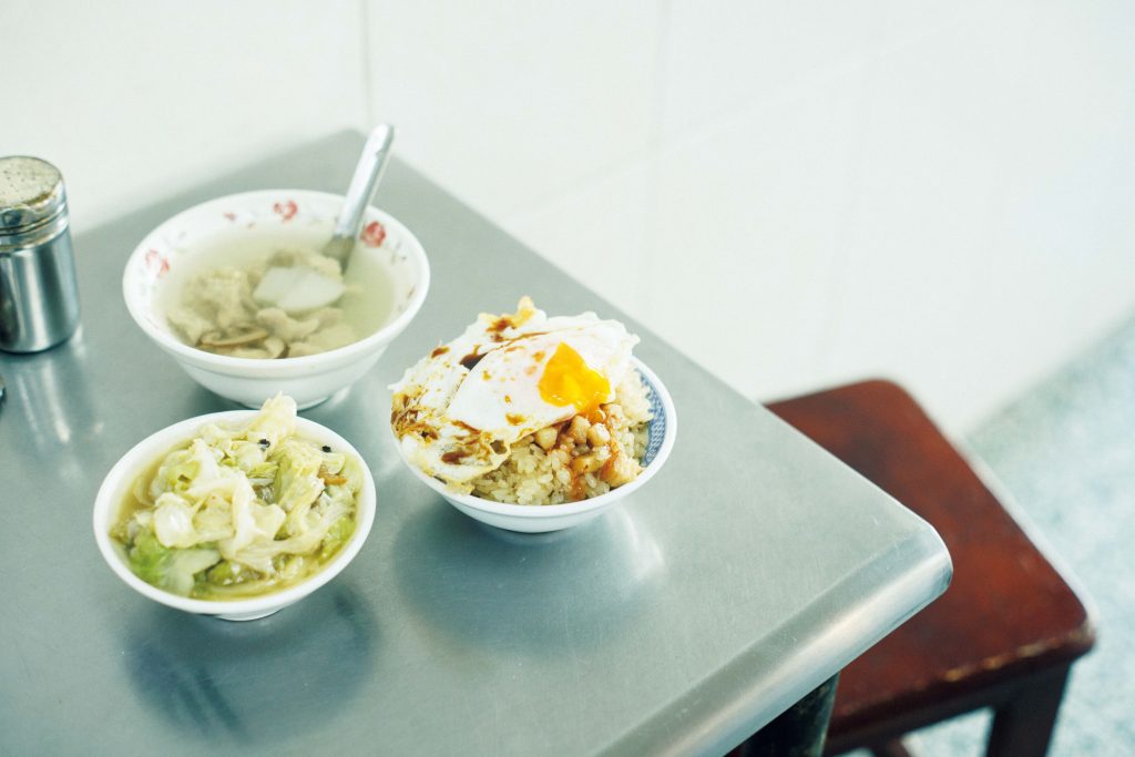 珠記大橋頭油飯の荷包蛋（フーパオダン）と肉焿湯（ロウゲンタン） | 右は、アヒルの卵を揚げ焼きした荷包蛋（フーパオダン）（25元）をのせた油飯40元。上のスープは、豚骨スープに豚のつみれ、大根、しいたけが入った肉焿湯（ロウゲンタン）60元。