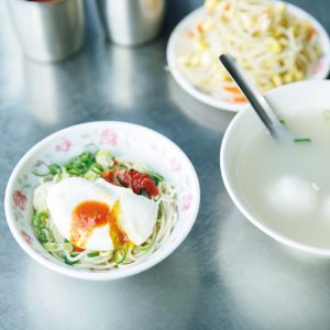 林家乾麵の蛋包魚丸湯（タンパオユィワンタン） | 乾麵（小）37元。右は豚骨とエビのだしが効いた蛋包魚丸湯（タンパオユィワンタン）45元。「汁なしの合え麺とスープを一緒に注文するのが定番。スープの中
の卵を麺に移して食べるのが通の食べ方」と案内人の洪愛珠さん。