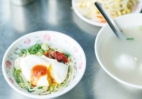 香り高い麺を気軽に。長く愛されてきた味を受け継ぐ人気店へ。乾麵（小）37元。右は豚骨とエビのだしが効いた蛋包魚丸湯（タンパオユィワンタン）45元。「汁なしの合え麺とスープを一緒に注文するのが定番。スープの中 の卵を麺に移して食べるのが通の食べ方」と案内人の洪愛珠さん。 | 乾麵（小）37元。右は豚骨とエビのだしが効いた蛋包魚丸湯（タンパオユィワンタン）45元。「汁なしの合え麺とスープを一緒に注文するのが定番。スープの中
の卵を麺に移して食べるのが通の食べ方」と案内人の洪愛珠さん。