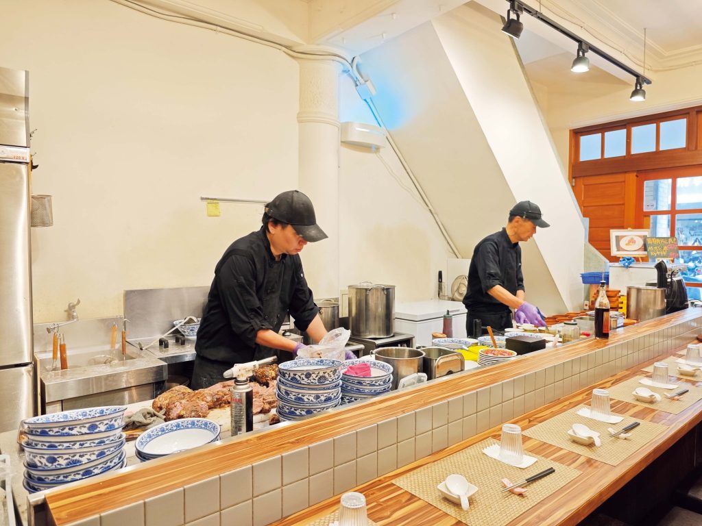 歩くたびに発見がある大稲埕（ダーダオツェン）歴史と文化の街を散策。後編1階はカウンター席のみ。11時に店前に設置されるボードに希望の時間帯と名前を記入し、指定時間前に戻ってくる仕組み。 | 1階はカウンター席のみ。11時に店前に設置されるボードに希望の時間帯と名前を記入し、指定時間前に戻ってくる仕組み。