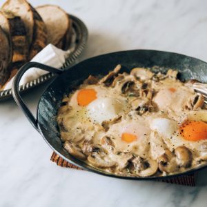 時間に余裕がある休日の朝は、心がリッチになる卵レシピを。「ごちそうの卵料理」。 | バターとにんにくが香る煮込み料理。とろっと流れ出る黄身ときのこの旨味が凝縮した出汁にパンを浸しながらどうぞ。