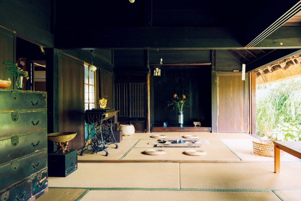 自然に近い茅葺き屋根での暮らし。富田晨さん、富田祐紀さんが実践する豊かな暮らし。南側の庭に開く2間。年中開け放して風を通している。奥の部屋には床の間がある。ここで昼寝をするのが気持ちいいとのこと。座って軒先が少し見えるのが、茅葺き屋根の伝統的な寸法だという。 | 南側の庭に開く2間。年中開け放して風を通している。奥の部屋には床の間がある。ここで昼寝をするのが気持ちいいとのこと。座って軒先が少し見えるのが、茅葺き屋根の伝統的な寸法だという。
