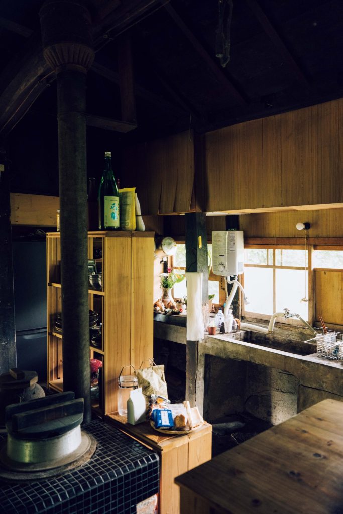 自然に近い茅葺き屋根での暮らし。富田晨さん、富田祐紀さんが実践する豊かな暮らし。 | 土間になっている台所。食器棚は自作した。タイルが張られたかまどは修理すれば使用可能。いずれは活用したいと考えている。