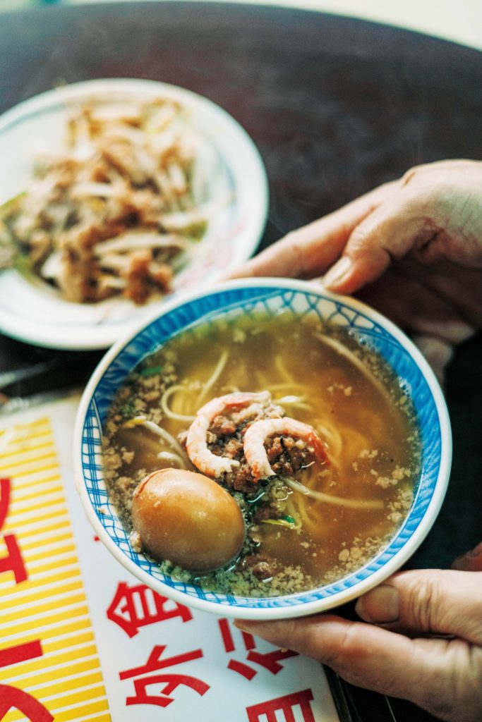 老若男女に愛される、地元ならではの味。台南フードを味わう。台南発祥の担仔麺（タンツァイミエン）小60元。すりおろし生ニンニク、パクチー、エビなどをトッピング。「栄養たっぷりな煮卵（15元）も欠かせません」と案内人で『蘿拉冷飲店 LOLA』オーナーのジンジンさん。 | 台南発祥の担仔麺（タンツァイミエン）小60元。すりおろし生ニンニク、パクチー、エビなどをトッピング。「栄養たっぷりな煮卵（15元）も欠かせません」と案内人で『蘿拉冷飲店 LOLA』オーナーのジンジンさん。