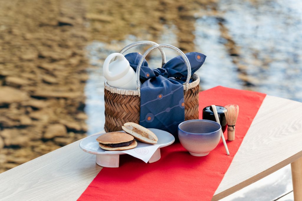 『あけぼのカフェ』のどらやきと深川萩の茶碗を詰めた茶箱セット。街の中心を流れる音信川のせせらぎを聴きながら、野点を楽しむひとときを。