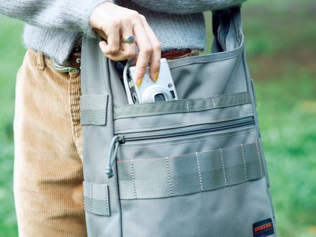 〈ブリーフィング〉DAY TRIPPER Lフロントにはスナップ付きポケットとジップポケットを設け、用途に合わせて使い分けられる。バッグの底にタックがあしらわれているため、ポケットに荷物を詰めてもメインの収納に干渉しにくい。 | フロントにはスナップ付きポケットとジップポケットを設け、用途に合わせて使い分けられる。バッグの底にタックがあしらわれているため、ポケットに荷物を詰めてもメインの収納に干渉しにくい。