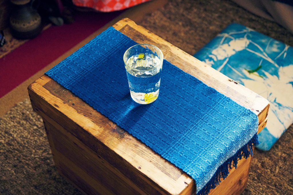 出西織のランチョンマット。 | ちゃぶ台代わりに使う茶箱の上には、出西織のランチョンマット。赤とベージュを基調とした空間の中で、藍色が差し色に。