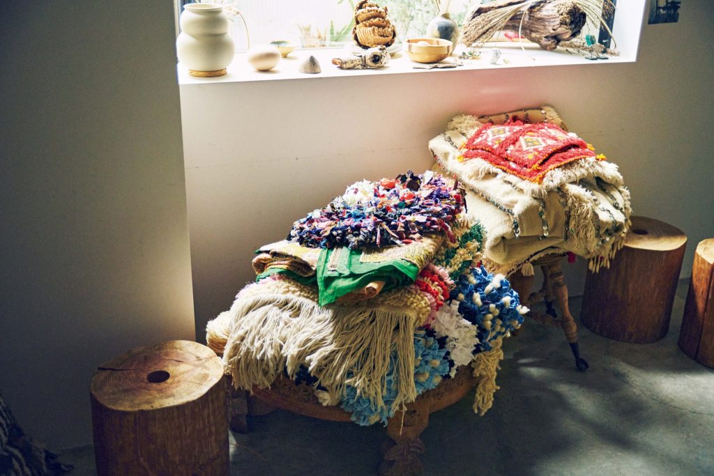 古着のＴシャツや着物などを織り込んで作られたボシャルウィット。 | スツールに積まれたマットは、古着のＴシャツや着物などを織り込んで作られたボシャルウィット。