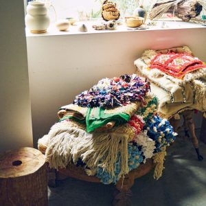 古着のＴシャツや着物などを織り込んで作られたボシャルウィット。 | スツールに積まれたマットは、古着のＴシャツや着物などを織り込んで作られたボシャルウィット。