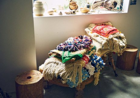 古着のＴシャツや着物などを織り込んで作られたボシャルウィット。 | スツールに積まれたマットは、古着のＴシャツや着物などを織り込んで作られたボシャルウィット。