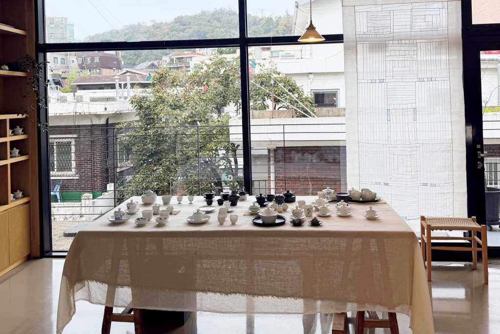 objectify　오브젝티파이　メインの展示エリア | 店の中心に据えられたテーブル越しに見えるのは、延禧洞の住宅街。ここがメインの展示エリアで、作品は定期的に入れ替わる。