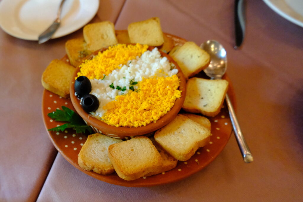 伝統と革新の食文化が交差するマカオで新たな味に出合う。 | Albergue 1601（アルベルゲ1601）　カニのペーストに炒り卵と玉ねぎを合わせてサラダ状に仕上げた「Sapateira Recheada （サパテイラ・レチェアダ）」は、濃厚なカニの風味がガーリックトーストと相性抜群。