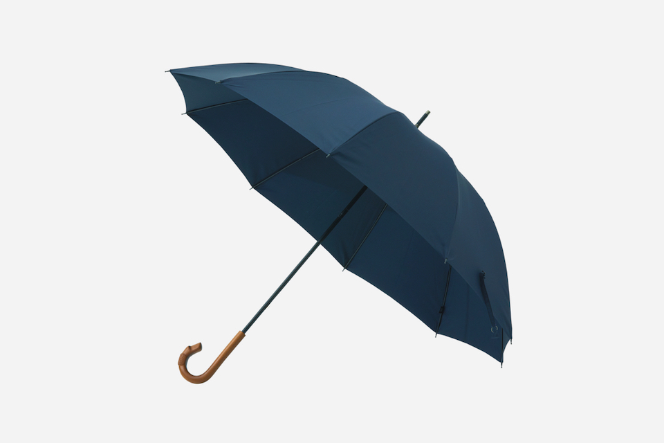 <strong>〈大森商店〉の雨傘</strong><br /> 職人の手で作られるさまざまなハンドルの傘が揃う〈大森商店〉。こちらは雨の日の外出を楽しくしてくれそうな、愛らしい犬の顔が掘られた雨傘。細身のシルエットやシックな色により、遊び心がありながらも洗練された表情に。持ち手のカーブが手にフィットして握りやすく、骨は丈夫で軽いカーボン素材を用いているので、使いやすさも文句なし。雨傘［φ102cm、長さ82cm］¥17,600 (☎︎03-3863-6414) 